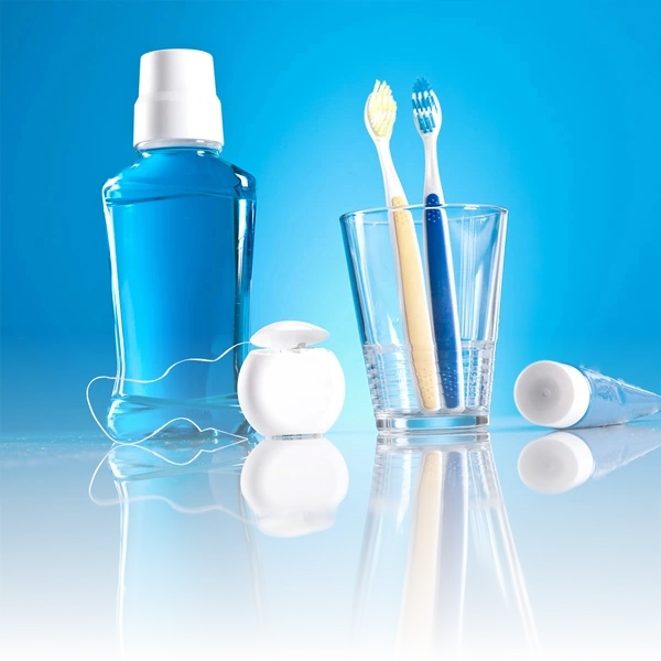 Itens essenciais de higiene bucal incluindo enxaguante bucal, fio dental, escovas de dente e pasta de dente, promovendo cuidados preventivos diários recomendados pela Clínica IPPO.