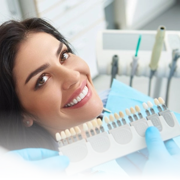 Paciente sorridente durante procedimento de seleção de cor de dentes para prótese ou facetas, em consulta odontológica para um sorriso estético.