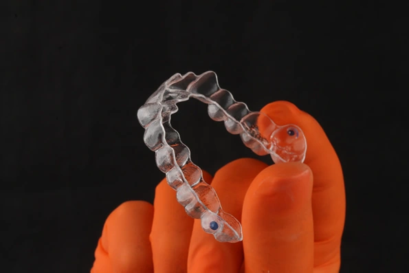 Alinhador invisível transparente, feito de placas de acetato personalizadas para tratamento ortodôntico, oferecendo discrição e conforto.